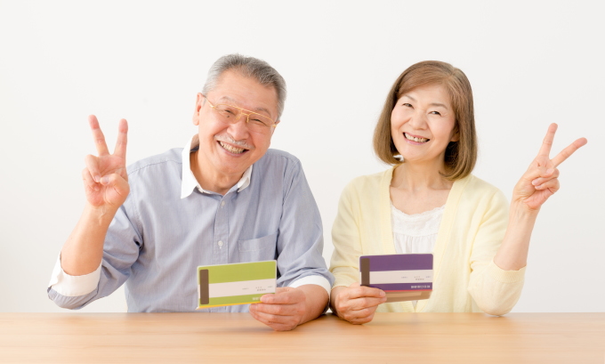 通帳を見て微笑む高齢の夫婦