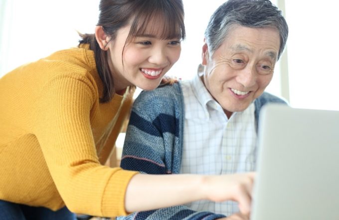 パソコンを楽しむ老人と教える若者
